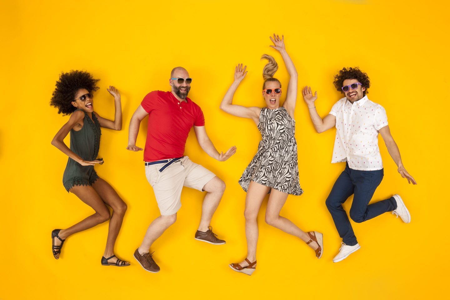 Group of millennials posing in front of a yellow backdrop