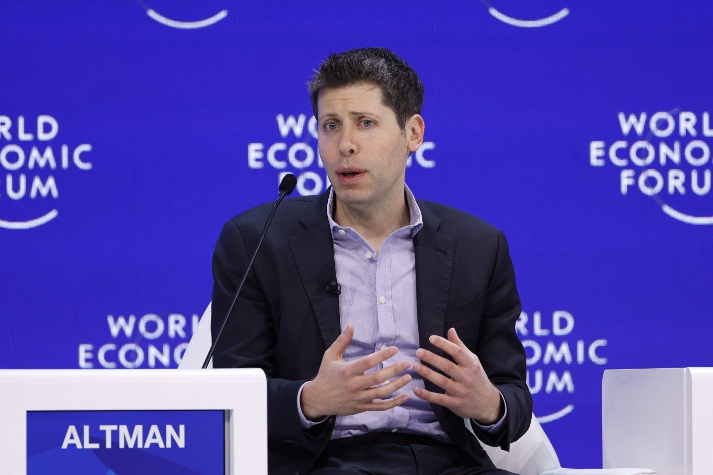 Sam Altman sits with hands out.