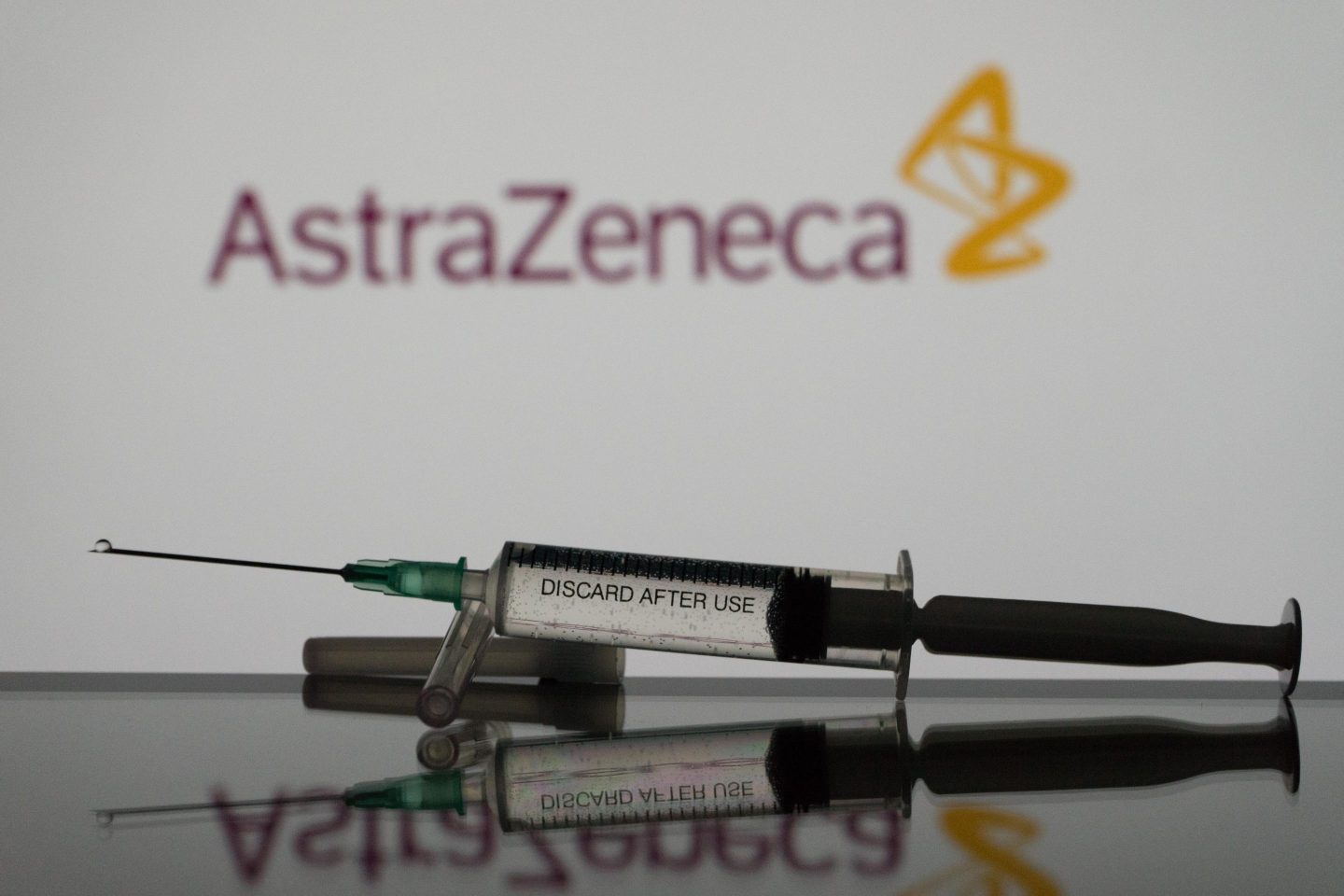 In this photo illustration a covid-19 vaccine is seen with the AstraZeneca logo in the background. (Photo Illustration by Nikos Pekiaridis/NurPhoto via Getty Images)