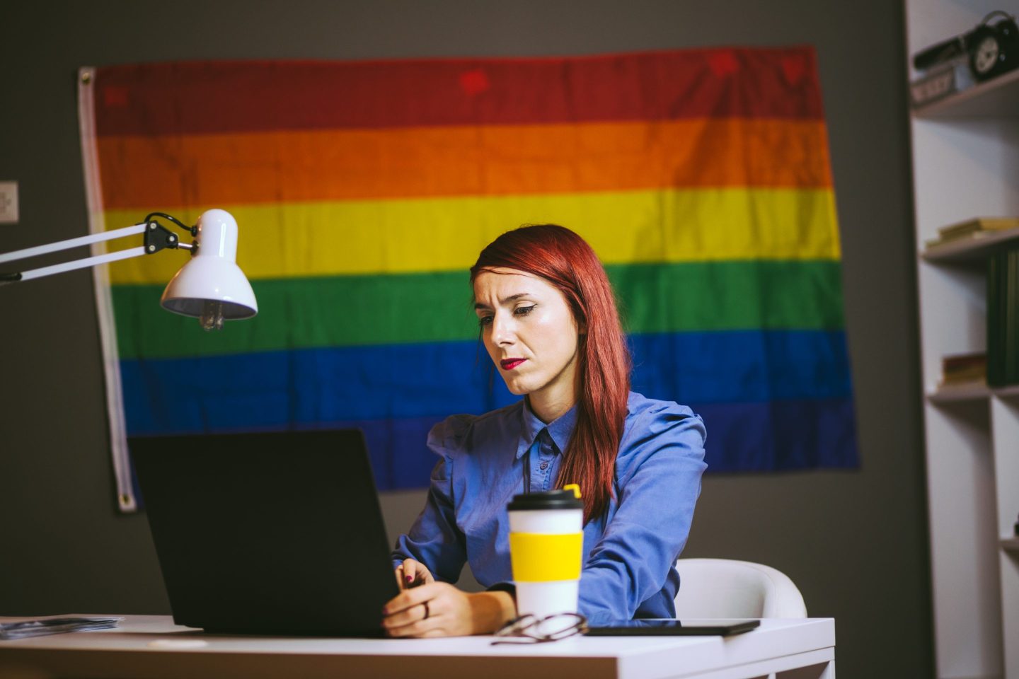 Worried LGBTQ+ employee sits at laptop and works.