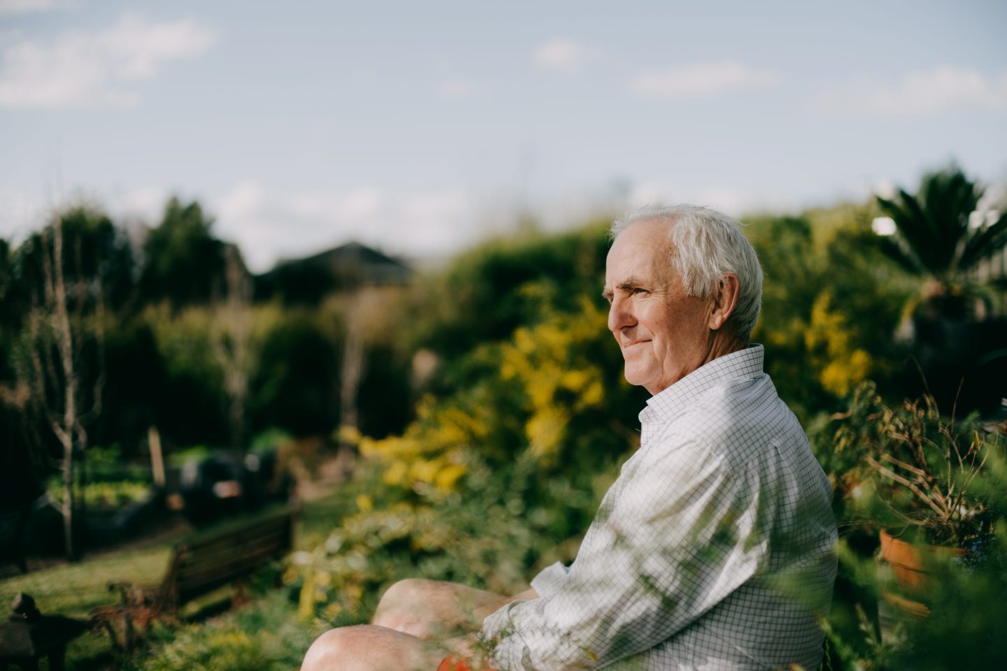 Confident senior man sitting in garden and looking at view, Melbourne, Australia.