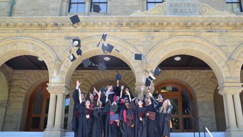 Graduates of the master's in international policy program throw their caps into the air.