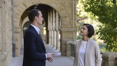 A man and a woman conversing outdoor at the entrance to Encina Hall, Stanford