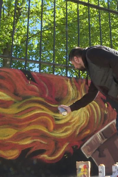 Sufyr, graffeur varois, met la dernière touche à la flamme olympique immortalisée sur le mur de l'école de Flassans-sur-Issole, où le relais passera vendredi 10 mai.