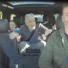 A group of people sit in a car, laughing.
