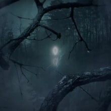 A figure seemingly made up of light stands in the distance in a dark forest.