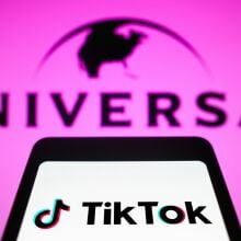 In this photo illustration, the TikTok logo is displayed on a smartphone screen with the logo Universal Music in the background.