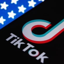 A phone displaying the TikTok logo on an American flag backdrop.