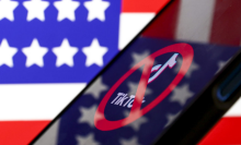 The TikTok logo with a cancellation symbol on top of it, displayed on a smartphone. It is in front of an American flag, which is also reflected on the smartphone screen.