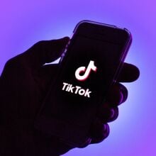A TikTok logo displayed on a smartphone with a purple background.