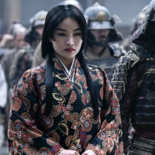 Mariko from "Shōgun," surrounded by her retinue of soldiers, wearing a black kosode patterned with red and gold flowers