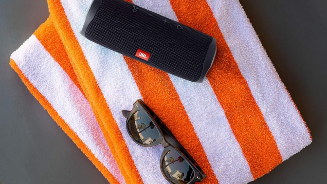 JBL portable speaker on orange and white beach towel 