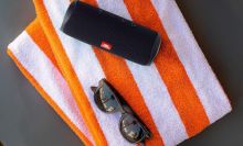 JBL portable speaker on orange and white beach towel 