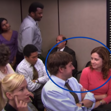 The cast of "The Office" sitting in a conference room. A man and a woman are circled.