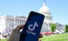 A phone displaying the TikTok logo in front of the White House. 