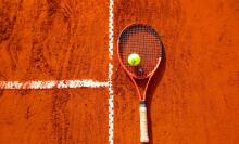 Tennis racket and ball on clay court