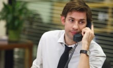 A man (John Krasinski as Jim Halpert on "The Office") sitting at a desk holding a phone to his ear.