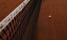Tennis net and ball on a clay court