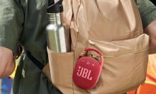 A JBL Clip 4 speaker is clipped onto a backpack
