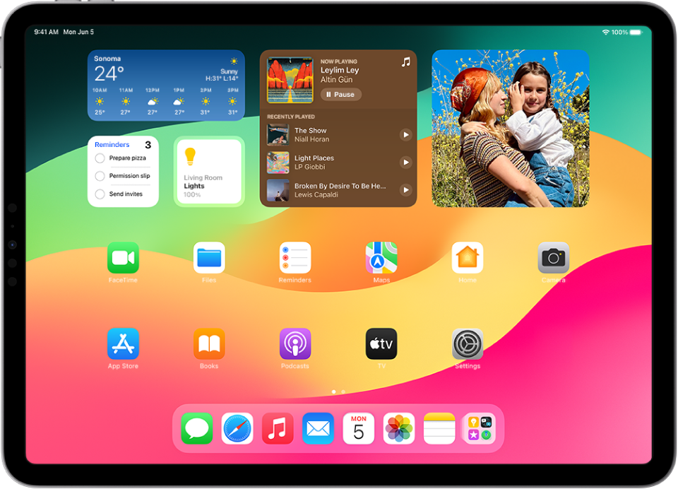 iPad ierīces sākuma ekrāns. Ekrāna augšdaļā ir logrīki Weather, Reminders, Home, Music un Photos. Logrīkiem Reminders, Home un Music ir interaktīvas funkcijas.
