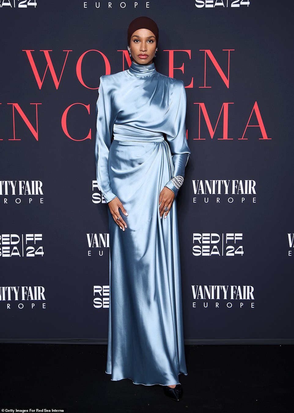 Ikram Abdi Omar looked ethereal in a baby blue, satin gown with long-sleeves and a mock neckline. The model sported black, pointed-toe shoes and rocked a chocolate brown hijab undercap as well as sparkling diamond jewelry
