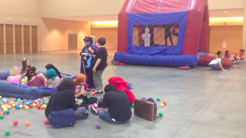 sad scene of a mostly empty convention hall with a single jumping castle and a tiny inflatable ball pit