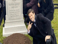 flash actor grant gustin standing over the grave of oliver queen from the dc comics television series arrow