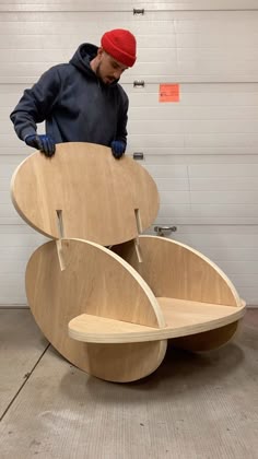 a man standing in front of a wooden chair that is shaped to look like a boat