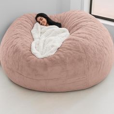 a woman wrapped in a blanket is sitting on a bean bag chair that's shaped like a bed