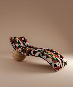 an artisticly designed chaise lounge chair with wood base and colorful fabric on the back