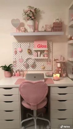 a desk with a pink chair in front of it and shelves on the wall behind it