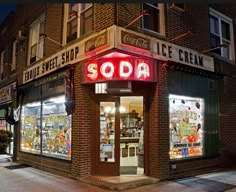 a soda shop on the corner of a street at night