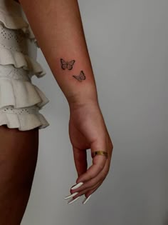 a woman's hand with a small butterfly tattoo on the left wrist and right arm