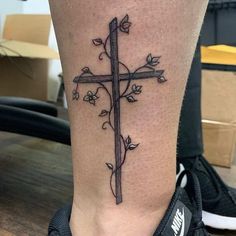 a cross with vines and leaves on the leg
