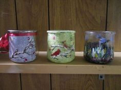 three painted glass jars sitting on top of a shelf
