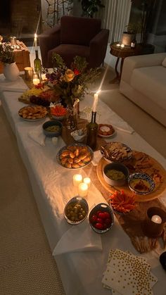 a table filled with food and candles on top of a white cloth covered long table