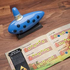 a blue toy boat sitting on top of a wooden table next to an open book