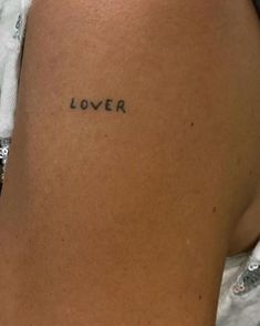 a woman's arm with the word lover tattooed on her left side, in black ink