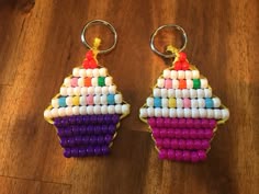 two key chains made to look like cupcakes on a wooden table with beads