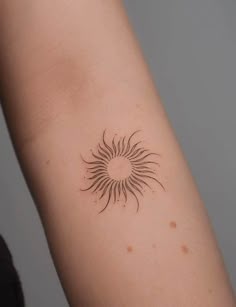 a woman's arm with a small sun tattoo on the back of her arm