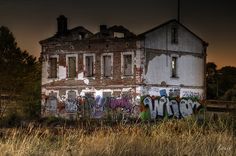 an old abandoned building with graffiti on it's side in the middle of nowhere