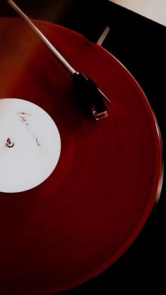 a red record player with a white disk on it's side and a black stick sticking out of the disc