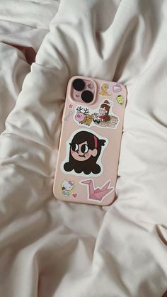 an iphone case with stickers on it laying on top of a white bed sheet