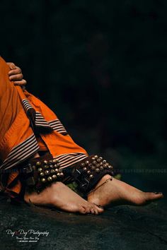 a woman is sitting on the ground with her legs crossed and wearing an orange dress