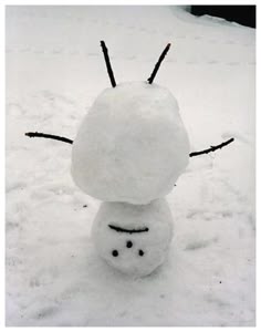 a snowman is standing in the snow with his head turned to look like he's smiling