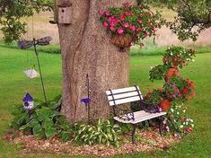 a white bench sitting next to a tree with flowers growing on it's sides