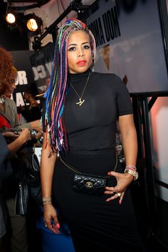 a woman with multicolored dreadlocks standing in front of a television screen
