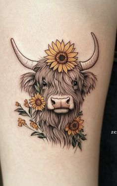 a cow with sunflowers on it's head is seen in this tattoo