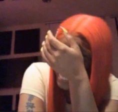 a woman with orange hair covering her face