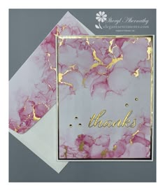 a pink and gold marbled thank card with the word thanks written on it in gold foil